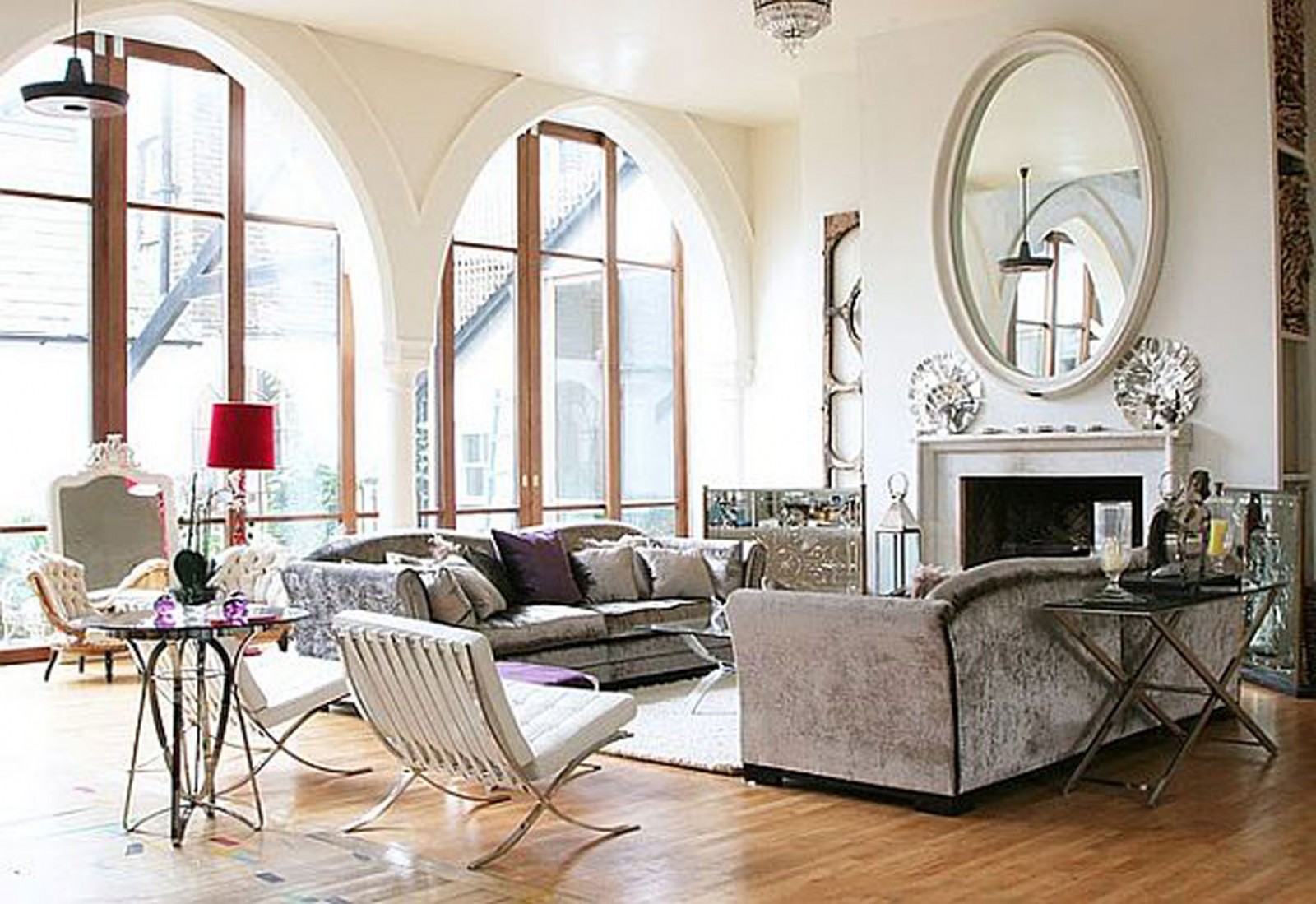  A living room with natural light from the arched windows, a large mirror, and a mix of modern and traditional furniture.