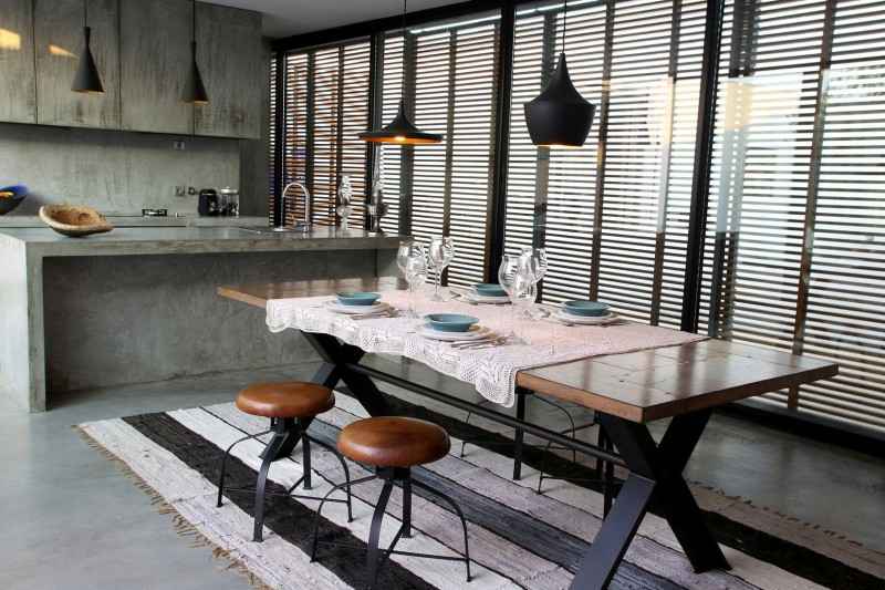 A modern kitchen with a wooden table and chairs showcasing texture mixing in home design.