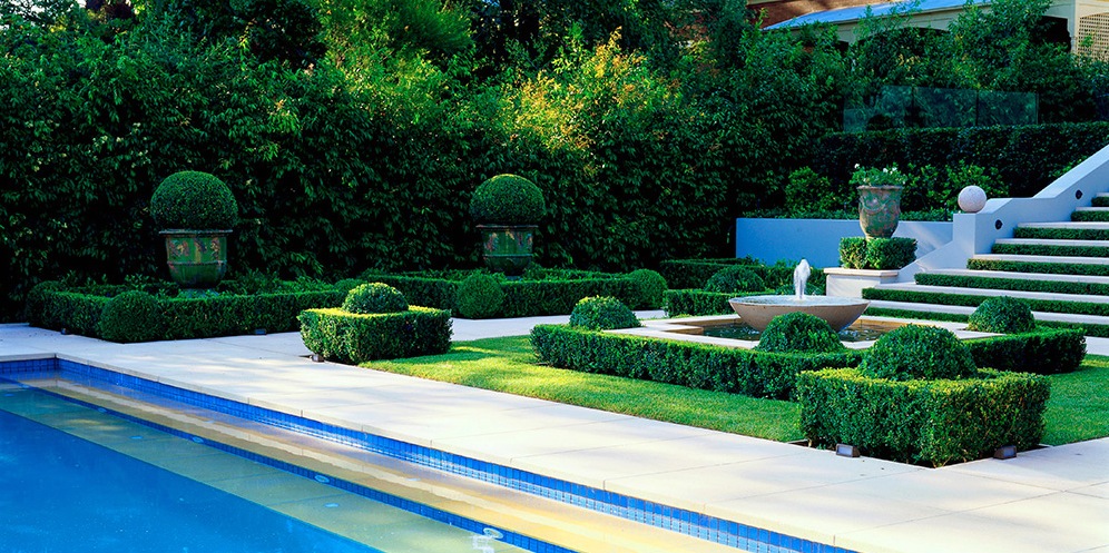 A classic manor house garden with a pool and a waterfall.