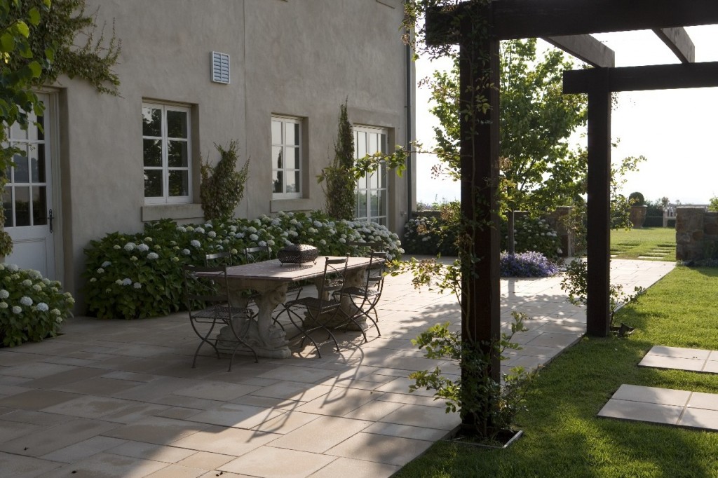 A classic manor house with a patio featuring a table and chairs in its garden.