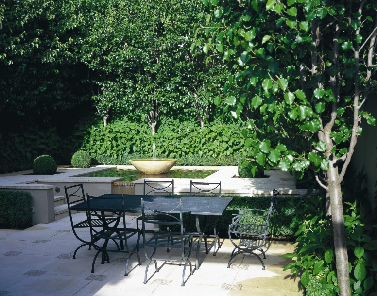 A classic garden with a fountain and table and chairs.