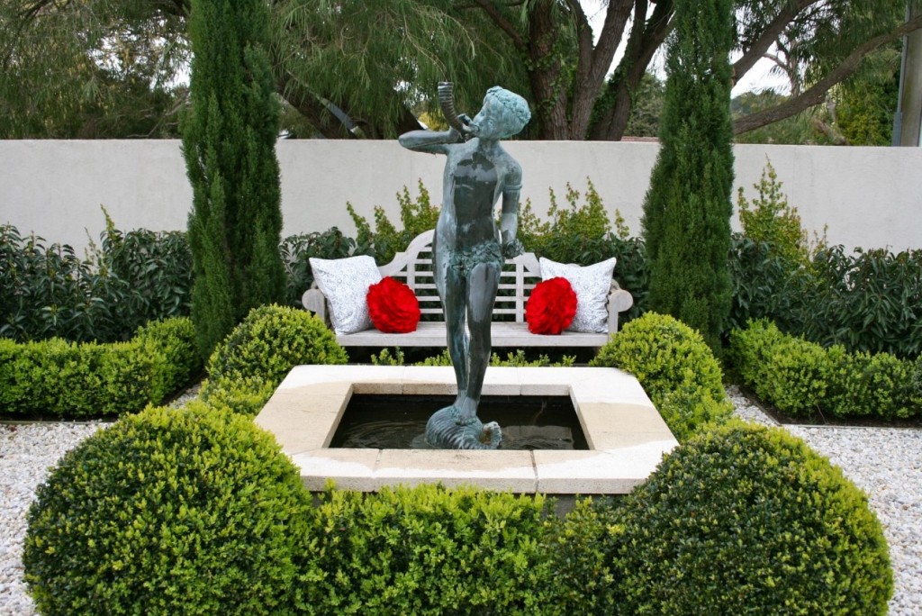 A statue adorns a bench in a classic garden.