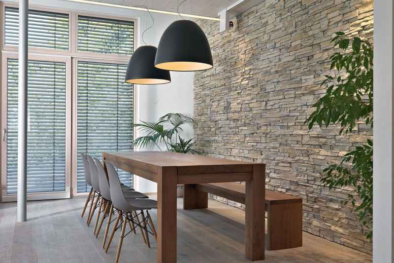 A dining room showcasing texture mixing with a stone wall and wooden table.