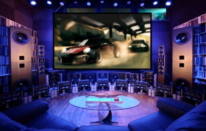 A gaming room with a large screen and speakers.
