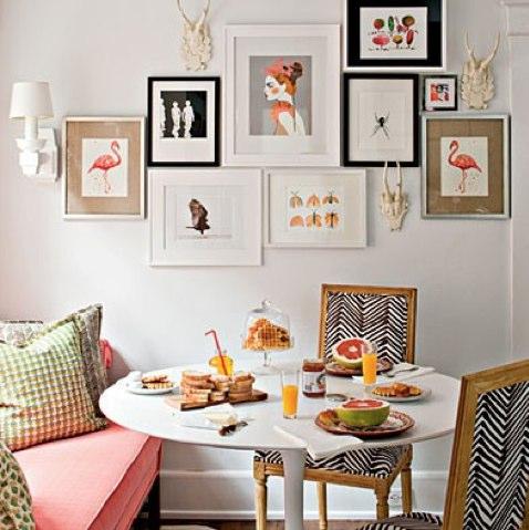 A dining room with a pink couch and framed pictures, designed to create a collage-like atmosphere.