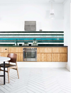 A kitchen with patchwork tiles and a wooden table.