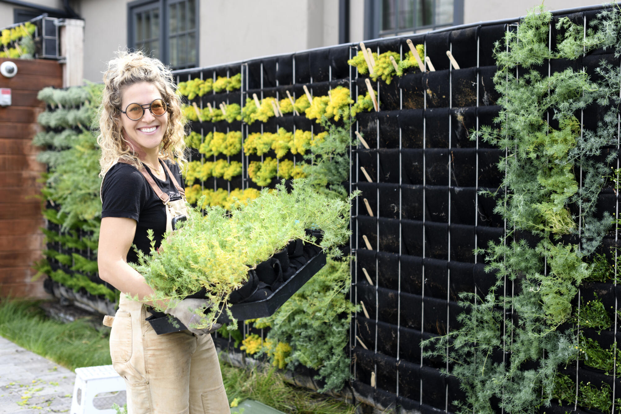 Woman gardening with vertical plant wall system.