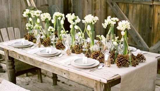 Winter floral arrangements featuring daffodils and pine cones on a wooden table.