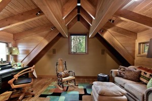 An attic apartment with wood beams and a desk.