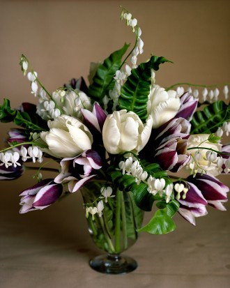 Seasonal floral arrangement featuring white and purple tulips and lily of the valley.