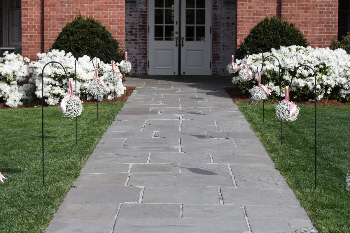 A home entry walkway adorned with white flowers and ribbons.