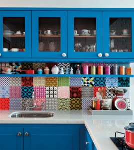 A blue kitchen with a patchwork tile backsplash.
