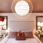 A bed in a bedroom with a lamp hanging over it, creating a focal point.