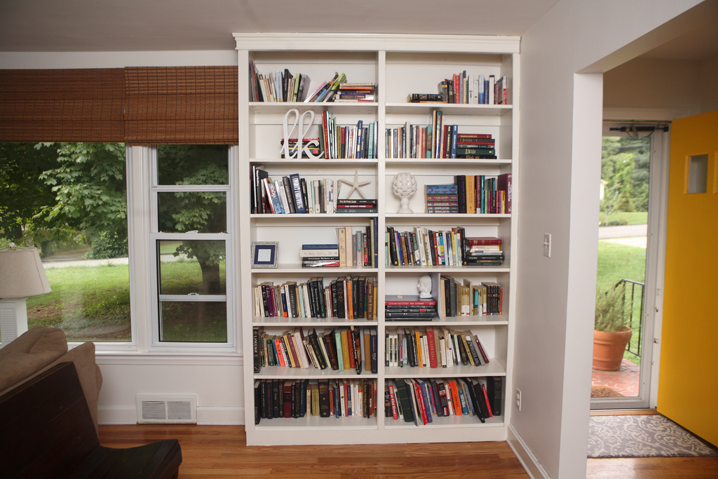 A large built-in white bookcase in a room with a yellow door.