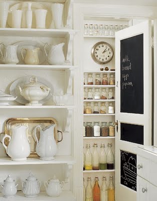 A kitchen with a chalkboard door, white pots and pans.