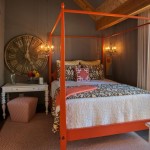 A guest room with an orange canopy bed and a clock.
