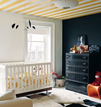 A baby's room with fun yellow and black stripe designs on the ceiling.
