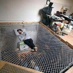 A man relaxing on a unique net bed in an office.