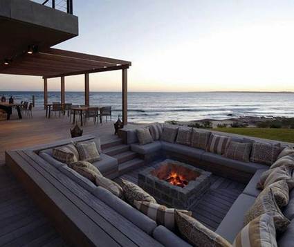 A deck with an outdoor fireplace overlooking the ocean.