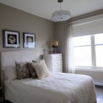A guest room featuring beige walls and a white bed.