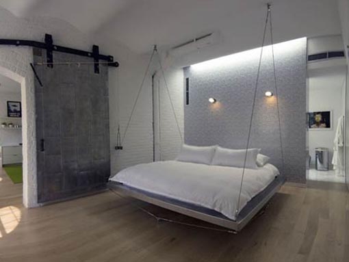 A unique bedroom with a bed hanging from the ceiling.