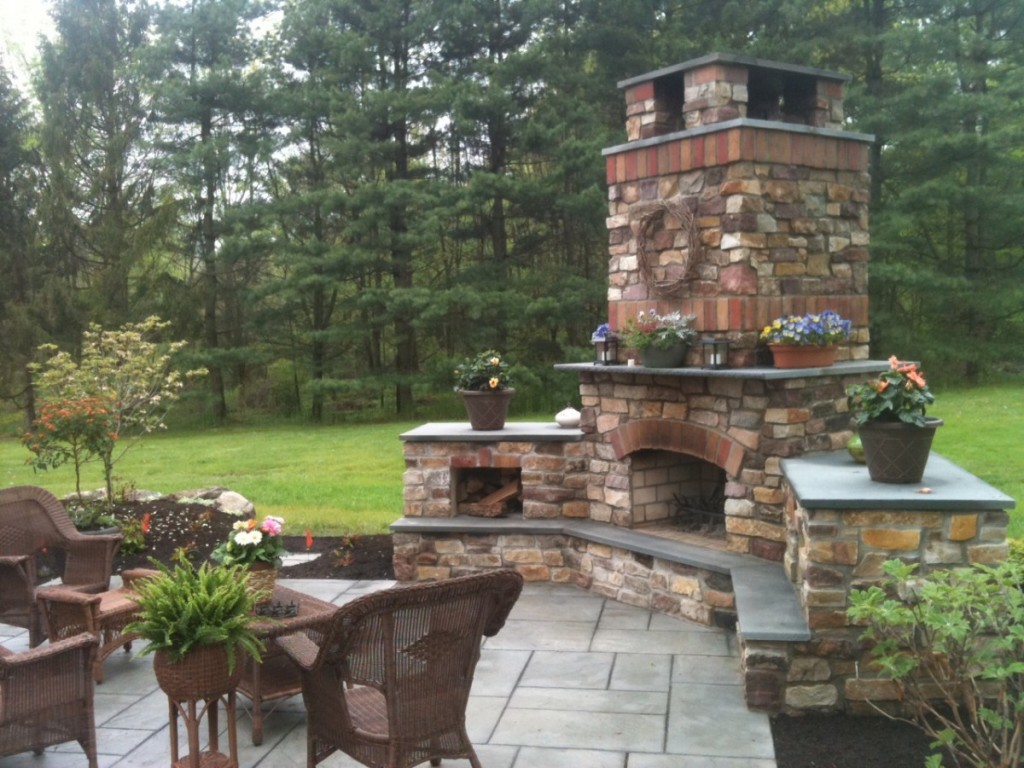 An outdoor patio featuring a stone fireplace and cozy furniture.