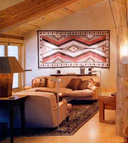 A living room with wooden beams and a rug.