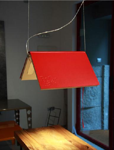 A red lamp hanging over a table in a room with books as design elements.