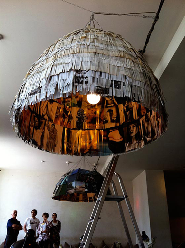 A large hanging lamp made out of newspaper, incorporating books as design elements.