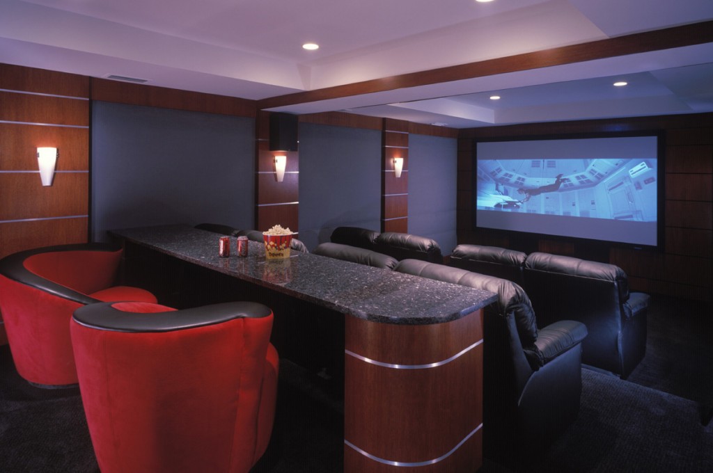 A movie room with red chairs.