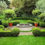 A garden with intricate shrubbery designs surrounding a fire pit in the middle.