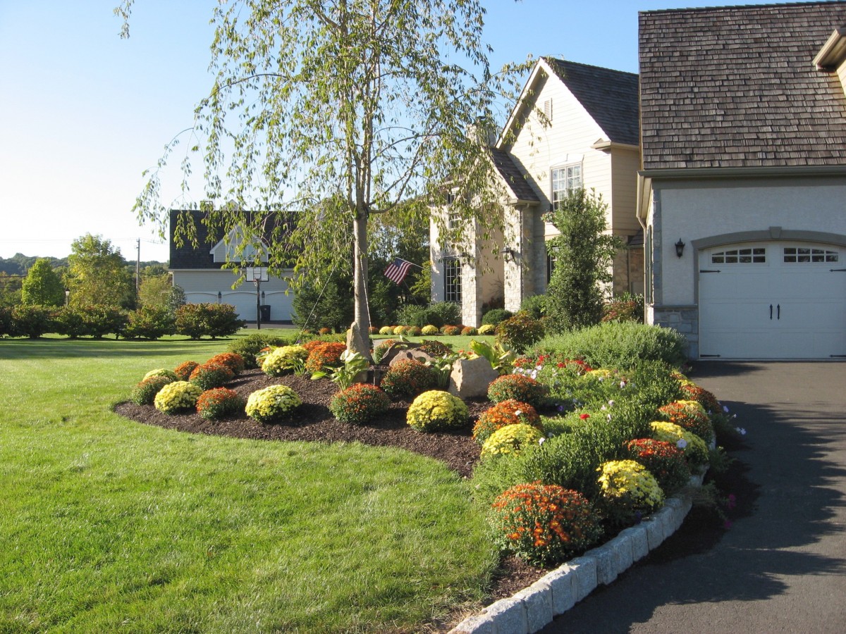 A flower bed adorns the driveway of a house.