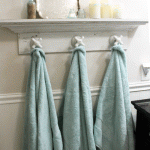 Three hand towels hanging on a shelf in a bathroom.