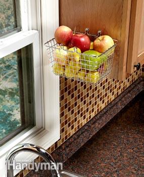 A kitchen counter decluttering solution with a sink and apple basket.