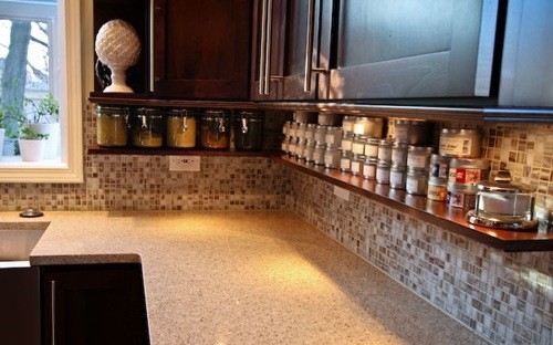 A cluttered kitchen counter with wooden cabinets and jars.