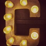A DIY light fixture with the letter c illuminated with light bulbs.