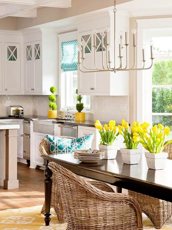 A festive kitchen with yellow wicker chairs and yellow tulips.