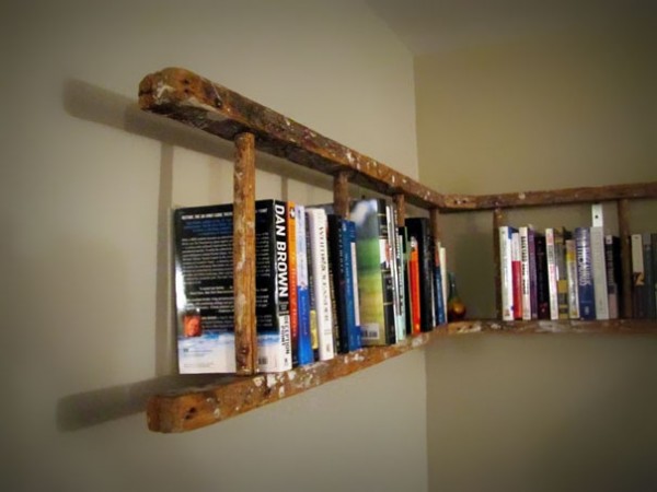 An upcycled ladder with books on it hanging on a wall.