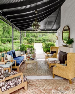 A covered outdoor patio with furniture and a fireplace.