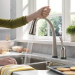A woman is washing her hands in a kitchen sink with a stylish faucet.