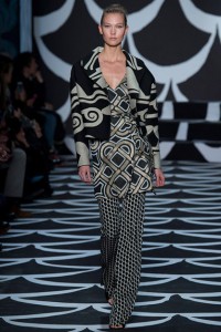 A model showcases a black and white patterned dress on the runway, embodying Fall 2014 design trends.