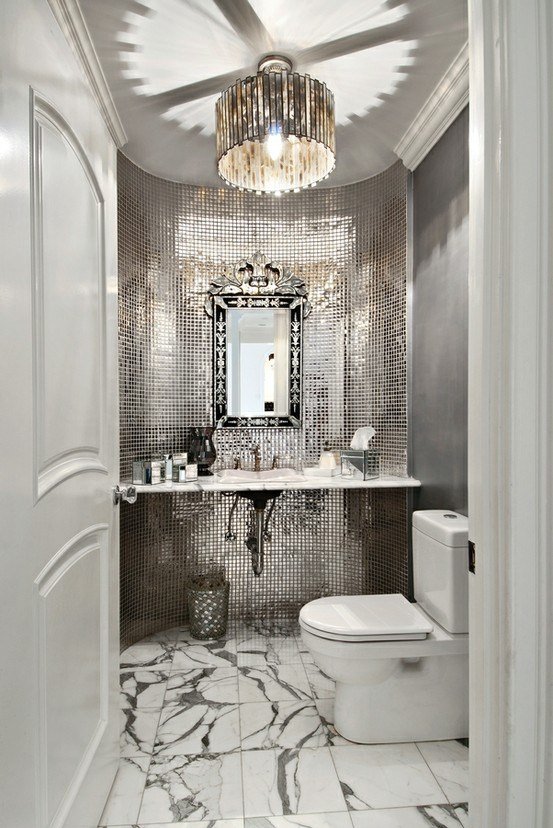 A powder room with a marble floor and a mirror.