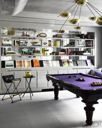 A fun room with a pool table and bookshelves.