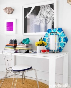 A white desk with colorful art and a chair in an apartment.