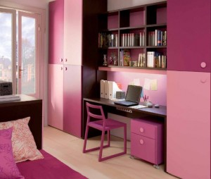 A small pink and white bedroom with a desk and bookshelf.