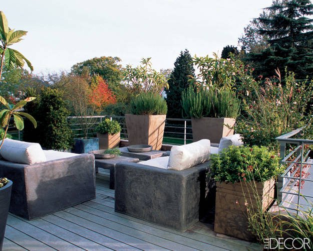 A wooden terrace with furniture and potted plants.