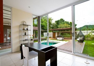 A room with floor to ceiling window and a pool.