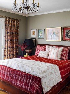 A red and white bedroom with a chandelier featuring mixing patterns.