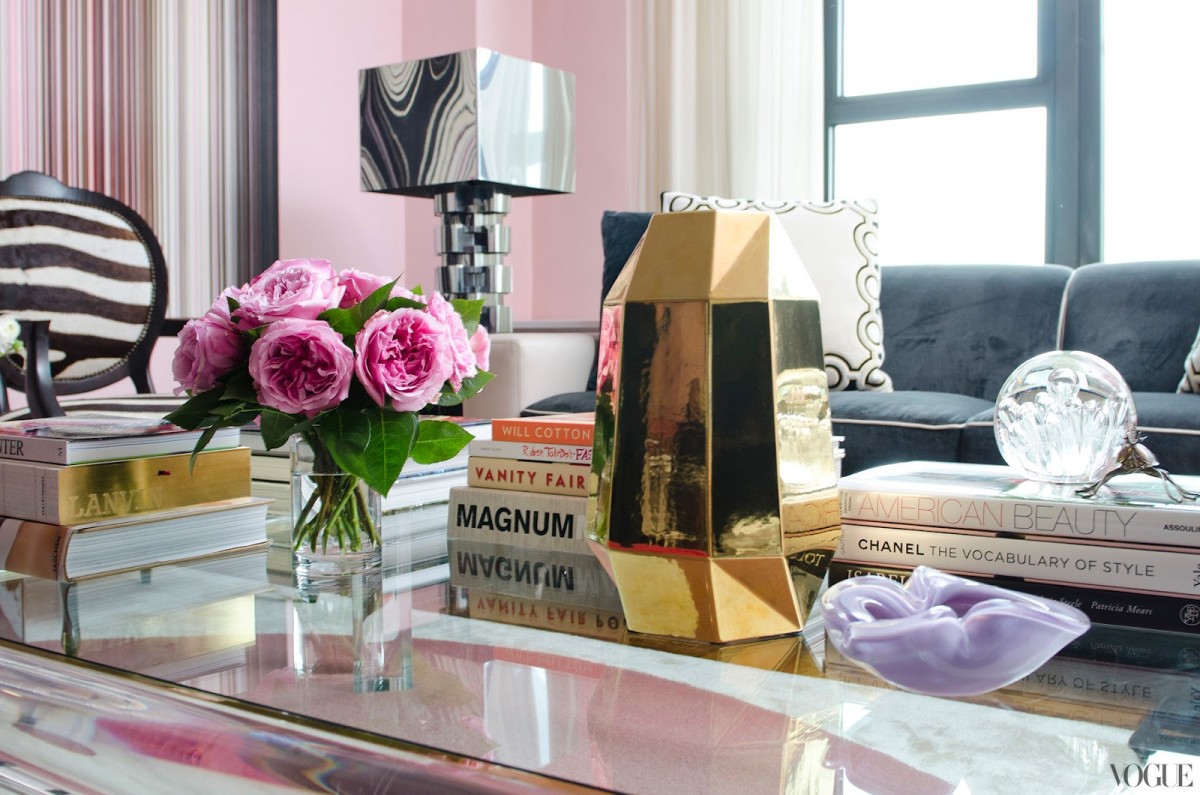 A living room with pink walls and a gold coffee table, accessorized to perfection.