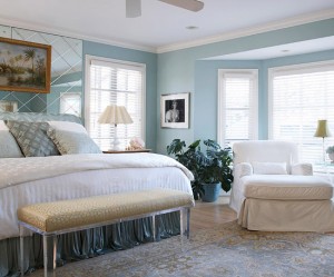 A casually elegant bedroom with blue walls and a white bed.